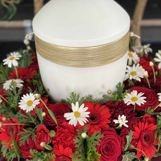 Urnenkranz in rot mit rosen, gerbera und weißer kamile - weiße urne für christliche beerdigung in paffenhofen ilm
