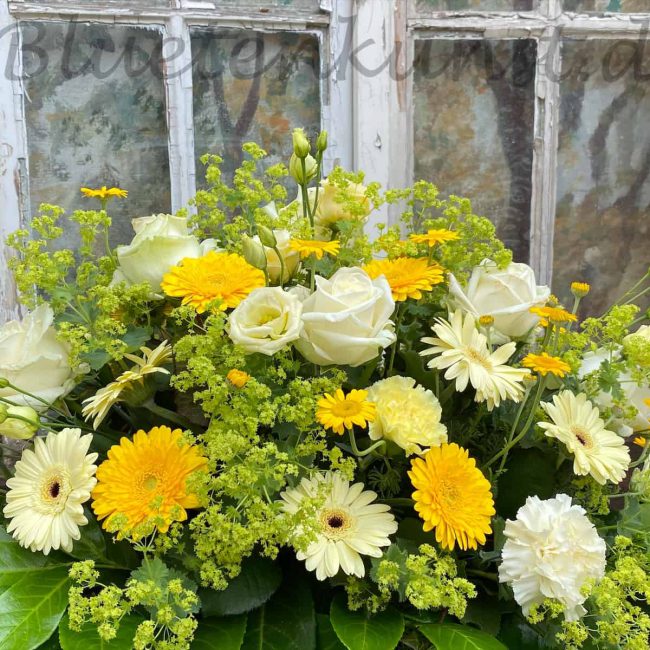 moderne Trauergestecke mit gelben Blumen Rosen, Gerbera im Hintergrund ein vintage Fenster für Beerdigung in Schrobenhausen moderne Trauerfloristk